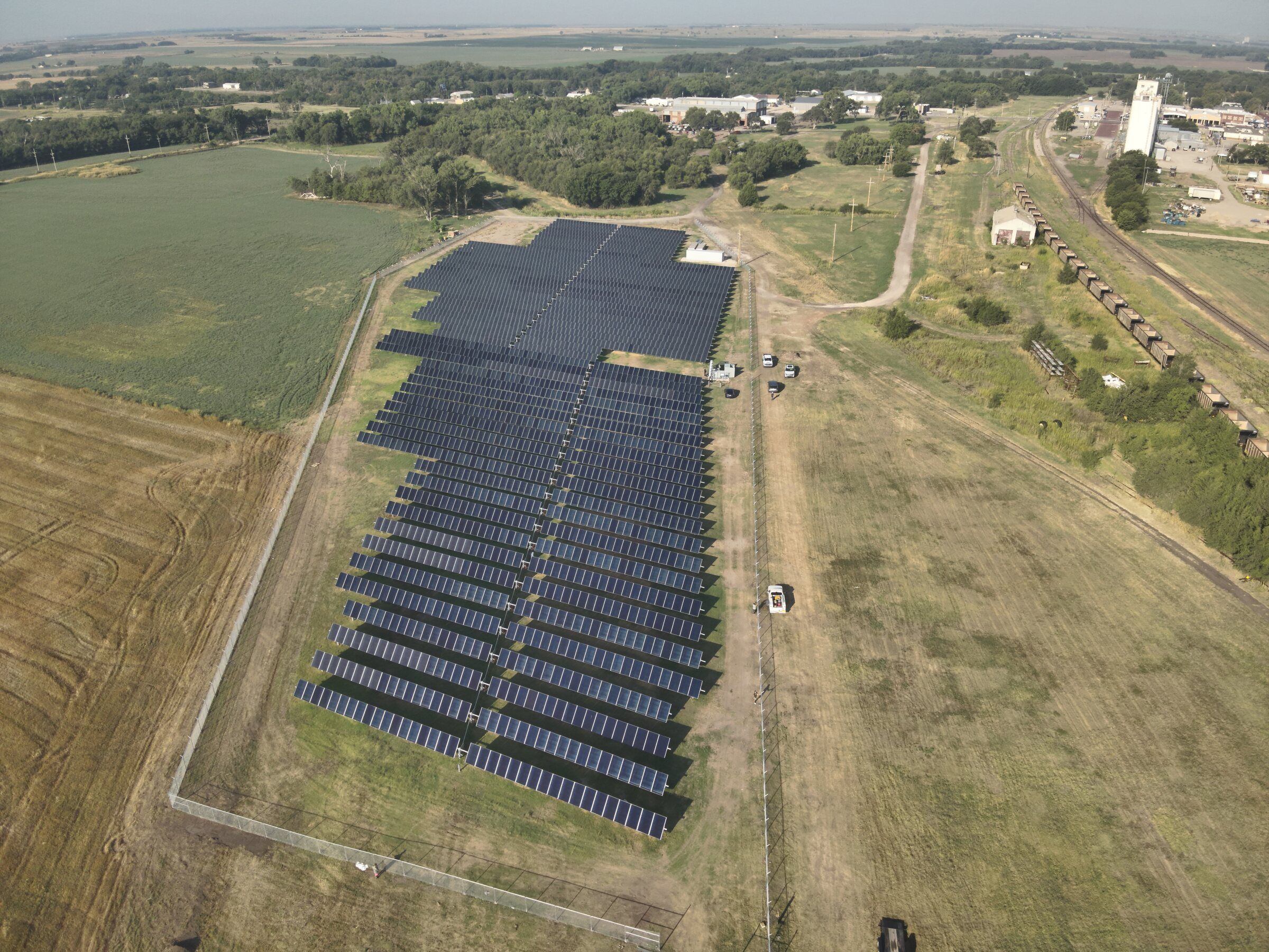 Ground-mounted single-axis tracker solar array beside farm fields in Hoisington, Kansas