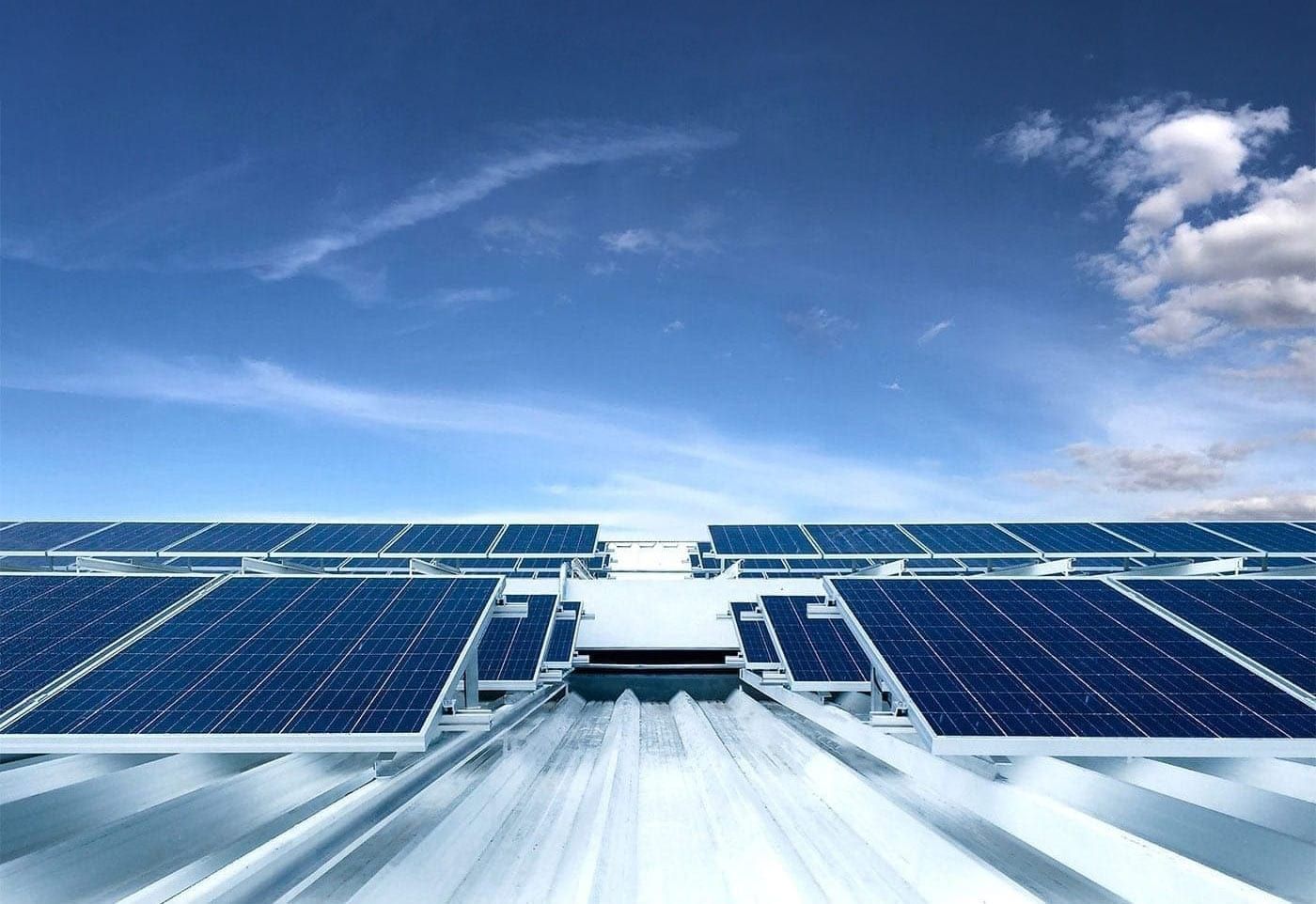 Rows of commercial solar panels on a metal roof under a blue sky